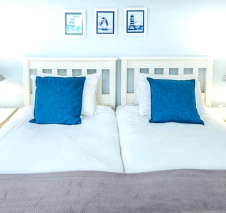 A bright beach house room showcasing a comfortable bed, decorated with light linens and beach-themed accents. A bright beach house room showcasing a comfortable bed, decorated with light linens and beach-themed accents.