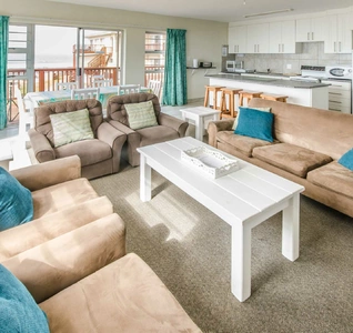 A spacious living room with comfortable couches, stylish chairs, and a table, inviting for gatherings and leisure.